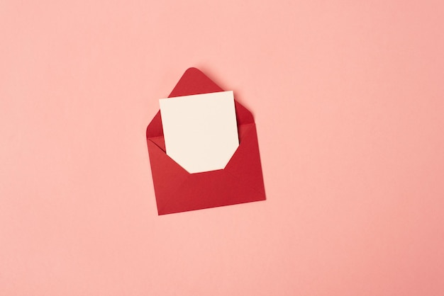 Bright red envelope with a blank sheet of paper on a pink background Copy space space for text