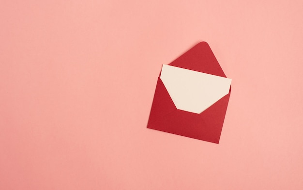 Bright red envelope with a blank sheet of paper on a pink background Copy space space for text