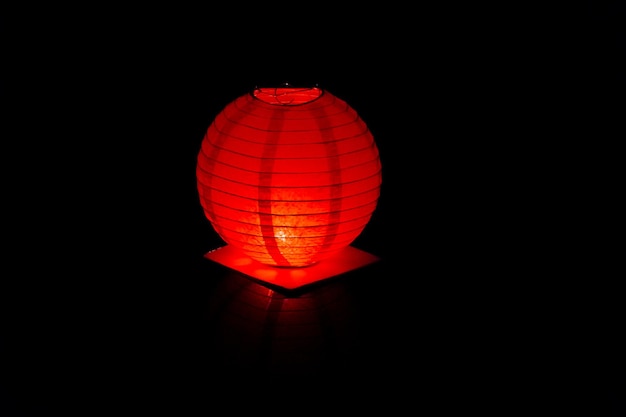 A bright red floating lantern in the black water