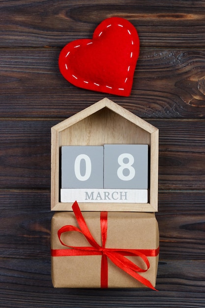 Bright red heart on wooden block calendar with gift box 8 march