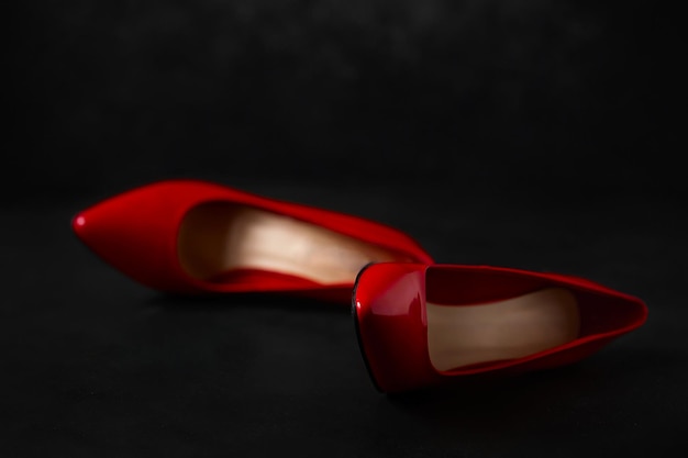 Bright red high-heeled shoes lie on a dark background