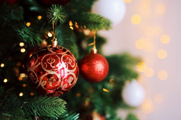 Bright red toy balls on the Christmas tree with lights