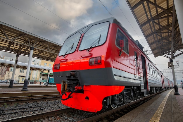 A bright red train stands on the platform of the railway station in the city Passenger Transportation