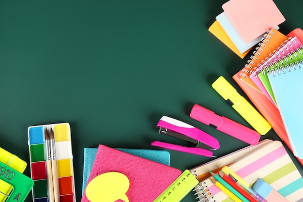 Bright school supplies on blackboard background