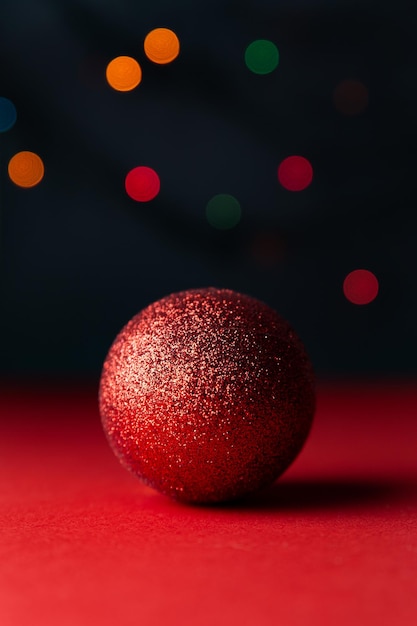 Bright shiny red ball with beautiful shadow on red background multicolored bokeh