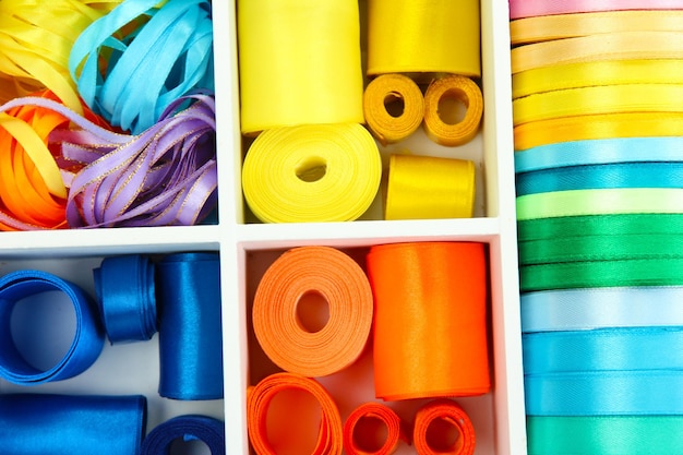 Bright silk ribbons in white wooden box close up