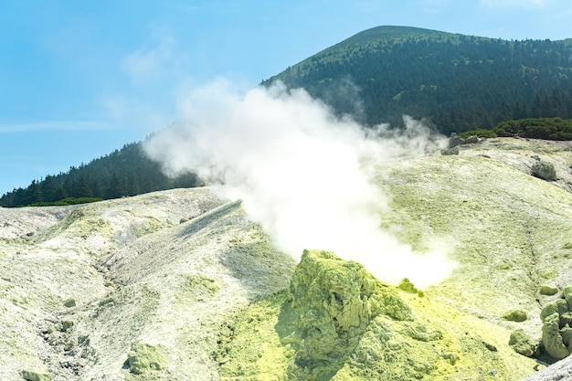 Bright smoking fumarole with sulfur deposits against the background of the Mendeleev volcano peak on the island of Kunashir