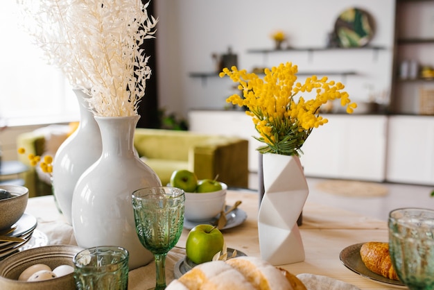 Bright spring mimosa in a ceramic geometric vase in the decor serving a festive or home table in the kitchen