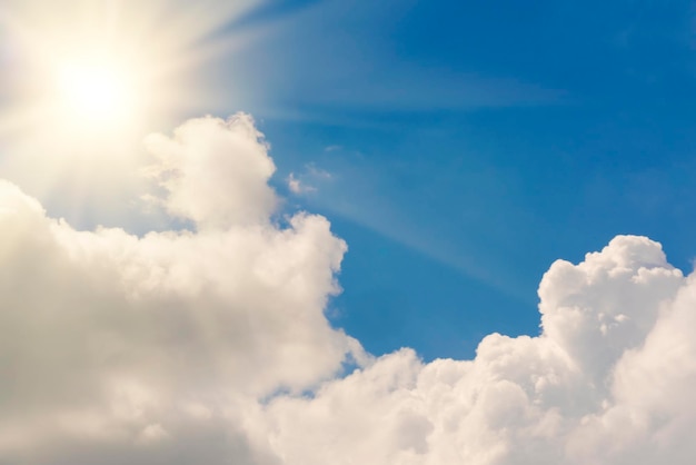 Bright sun on blue sky with white fluffy clouds background