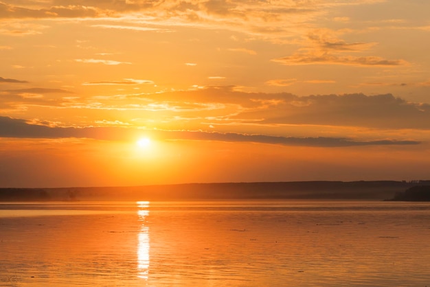 Bright sun in an orange sky over the water during sunset or sunrise