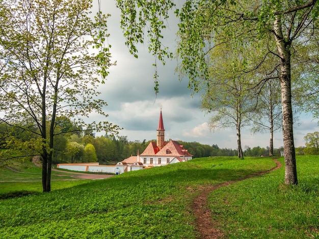 Bright sunny spring view with hiking path to the old white Maltese castle State Museum Reserve Gatchina Russia