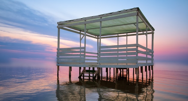 Bright sunset, and a bungalow on the water.