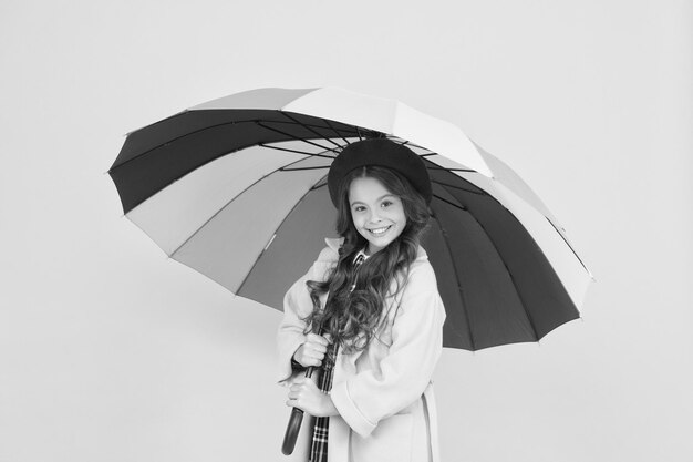 Bright umbrella Have fun Kid girl happy hold colorful rainbow umbrella Rainy weather with proper garments Positivity concept Rainy day fun Happy walk under umbrella Enjoy rain concept