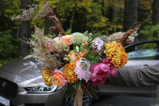 Bright unusual elegant autumn bouquet in the hands of the groom