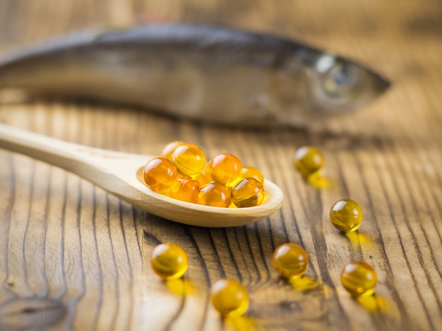 Bright wooden spoon with capsules of fish oil and fish