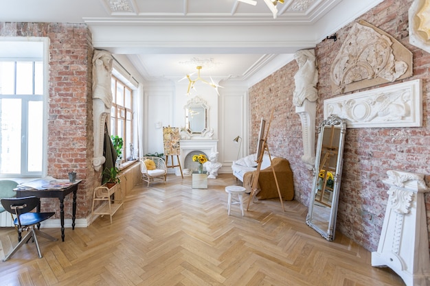 Bright workshop room for the creation and work of an architect and artist in a loft style with brick walls and parquet. the walls are decorated with examples of stucco.