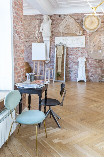 Bright workshop room for the creation and work of an architect and artist in a loft style with brick walls and parquet. the walls are decorated with examples of stucco.