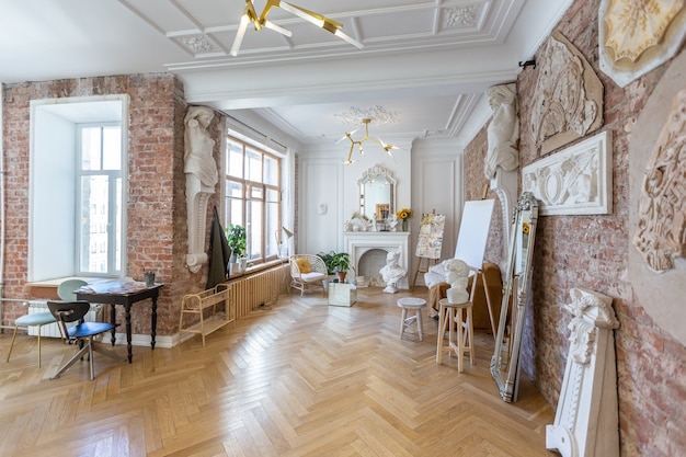 Bright workshop room for the creation and work of an architect and artist in a loft style with brick walls and parquet. the walls are decorated with examples of stucco.