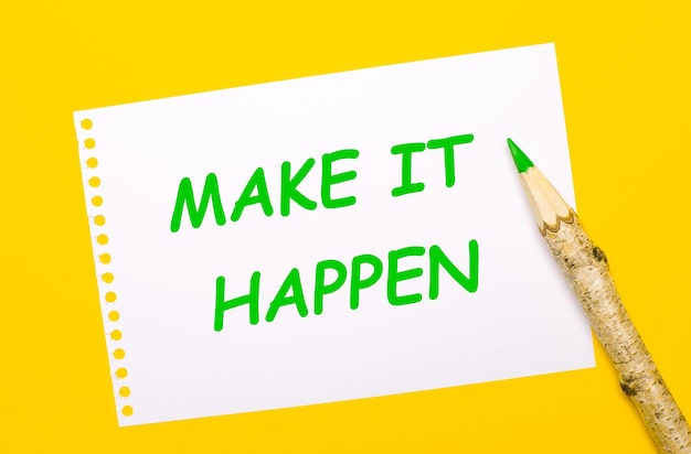 On a bright yellow background a large wooden pencil and a white sheet of paper with the text MAKE IT HAPPEN