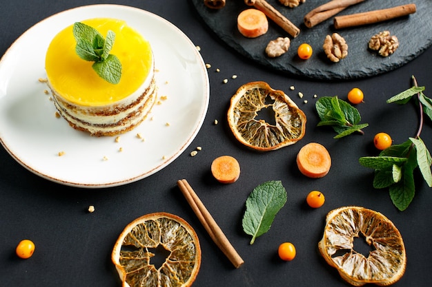 bright yellow diet carrot cake on a dark table dried orange cinnamon nuts mint leaves