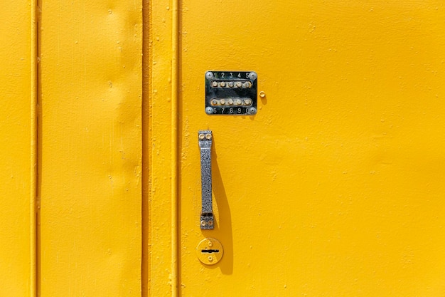 Bright yellow metal front door with an old combination lock Front view Space for text