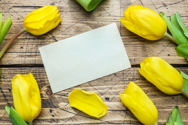 Bright yellow tulips on wooden background with copy space.