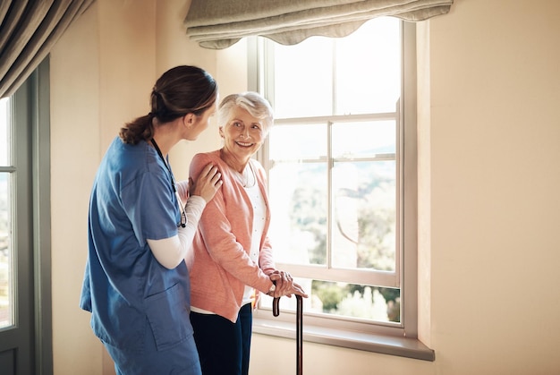 Brighter days are here because of you Shot of a young nurse standing with a senior woman next to a window in a nursing home