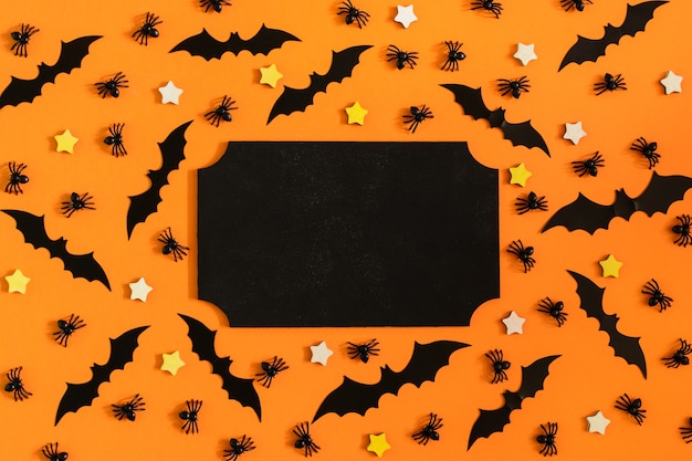 On a brightly orange surface, many ornamental spiders, bats and small stars are laid out.