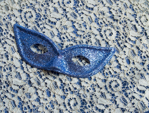 Brilliant blue carnival mask lies on beautiful lace Fashion background