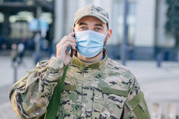 A British soldier stands outside a bus stop calling on a cell phone.