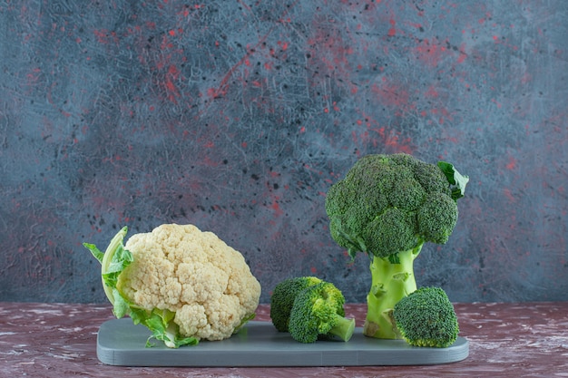 Broccoli and cauliflower on a board on the marble surface