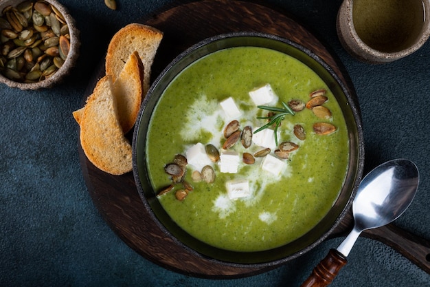 Broccoli cream soup in a bowl with toasted bread and cheese