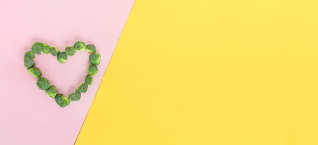 Broccoli heart on minimal pink yellow background Place for your text Copyspace