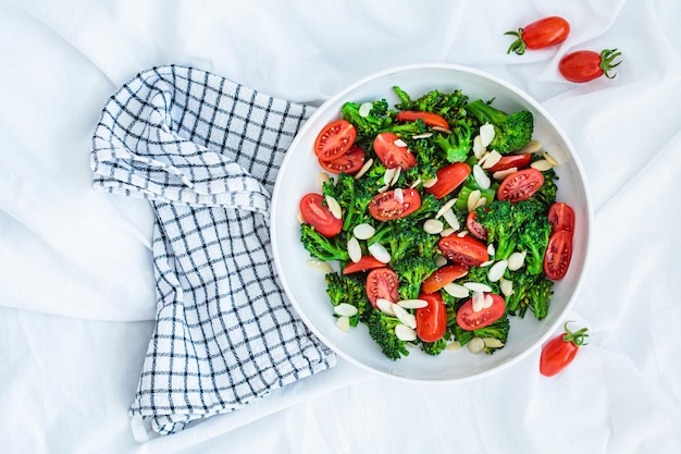 Broccoli salad with cherry tomatoes and almonds in white bowl Vegan detox recipe