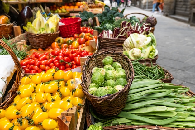 Broccoli, zucchini, green beans, brussels sprouts and red tomatoes in baskets at local farmer's market .