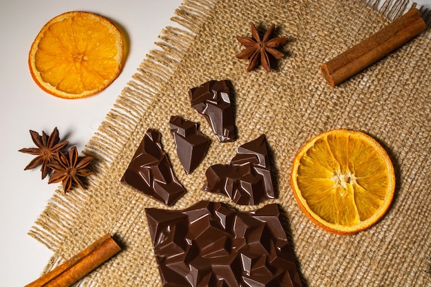 Broken bar of chocolate near a cup of cinnamon and orange tea