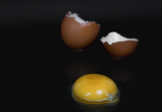 Broken chicken egg on black background close up