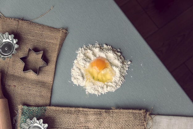 Broken chicken egg into flour with rolling pin and forms for baking