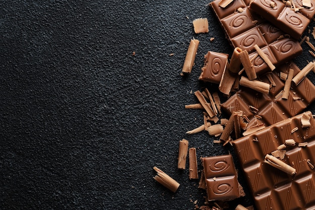 Broken chocolate bars on dark surface