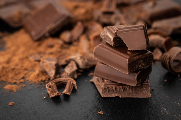 Broken chocolate pieces and cocoa powder on a dark background.