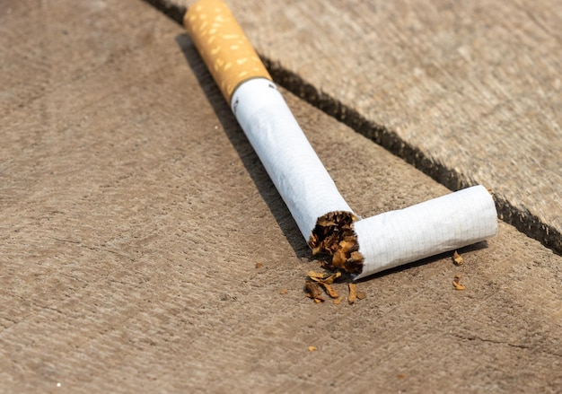 Broken cigarette closeup on a wooden table No smoking or antismoking movement A cigarette is broken on a wooden table and tobacco powder comes out Cigarettebanned concept