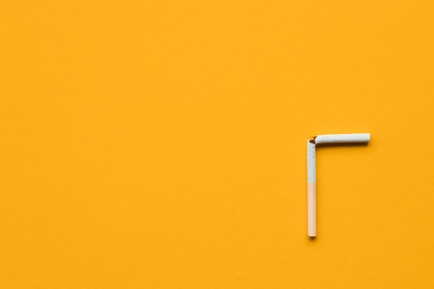 Broken cigarette on a yellow background No smoking concept