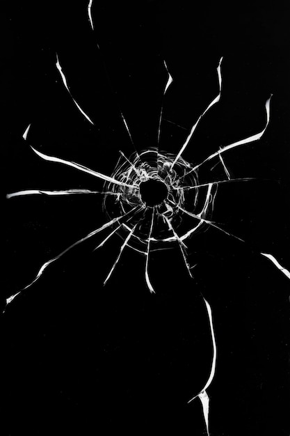 Broken glass shot crack texture with bullet hole on black background