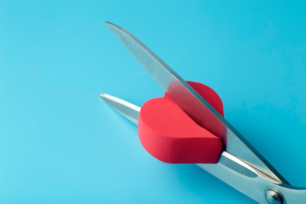 Broken heart cut with scissors on a colored background. Unhappy love