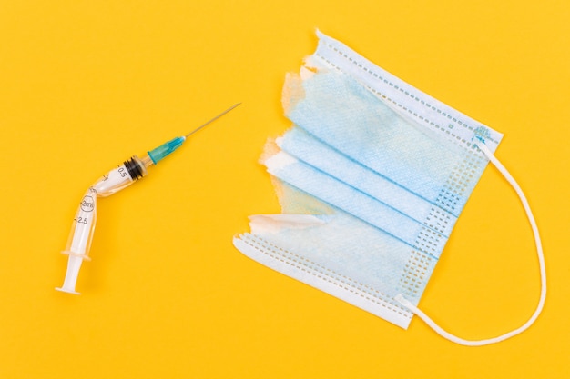 Broken medical syringe and torn medical face mask