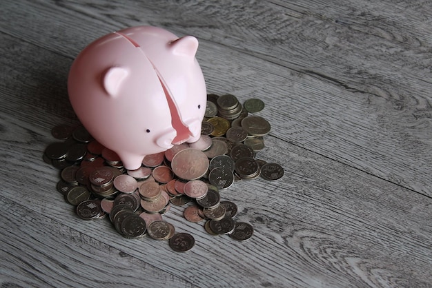 Broken piggy bank and coins on wooden table with copy space Financial concept