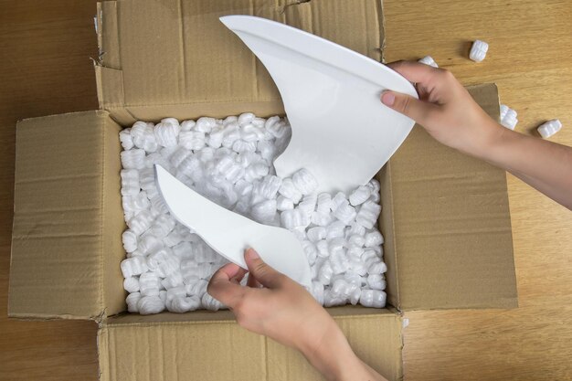 Broken plate in damaged cardboard box top view damaged home delivery unpacking box