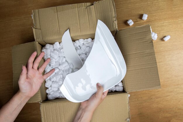 Broken plate in damaged cardboard box top view damaged home delivery unpacking box