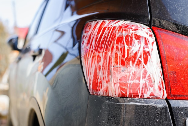 Broken red taillight of a black car wrapped with tape closeup