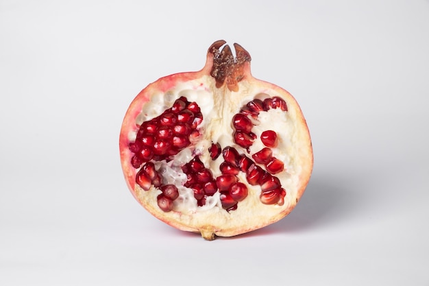 Broken ripe pomegranate fruit on a white surface. 